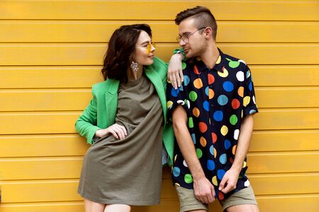 Young fashionable couple on yellow backgroundの写真素材