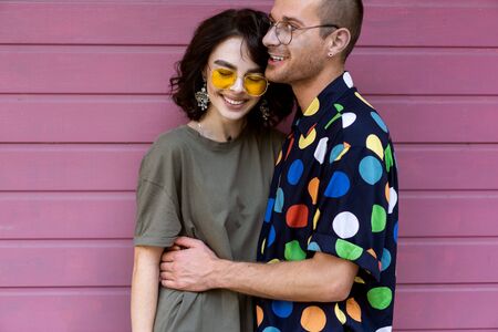 Young fashionable couple on pink backgroundの写真素材
