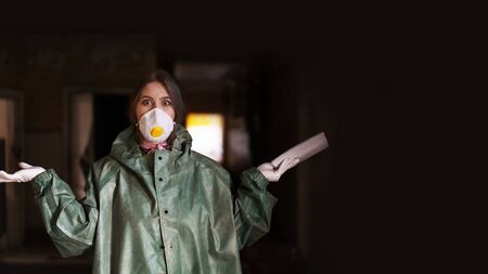 girl medic in a mask and a protective suit stands in the clinic with documentsの写真素材