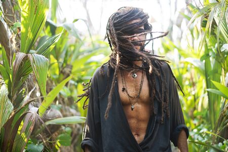 fashion guy with dreadlocks in tropical palm trees smilingの写真素材