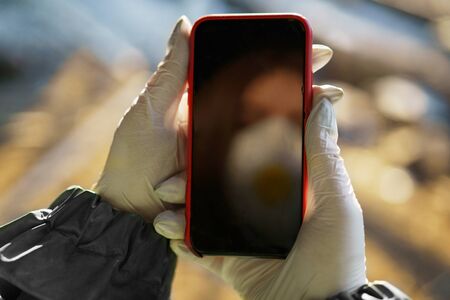 girl medic in a mask and a protective suit stands in the clinic holds the phone in his handの写真素材