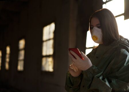 girl medic in a mask and a protective suit stands on the streetの写真素材