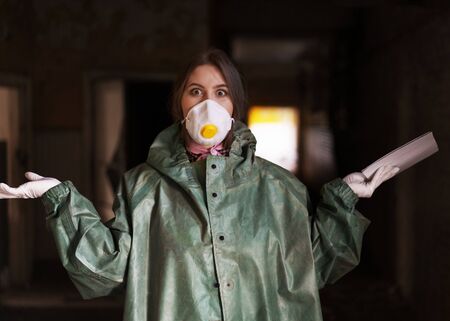 girl medic in a mask and a protective suit stands in the clinic with documents for coronavirusの写真素材