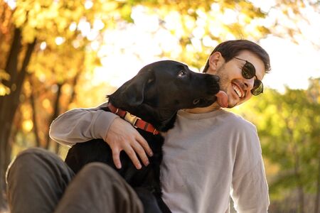 guy in sunglasses hugs his dog in autumn parkの写真素材