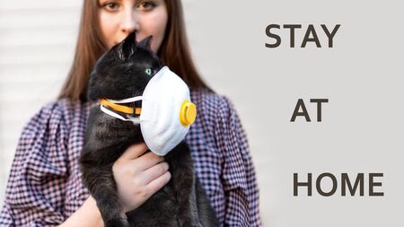 Girl Holding Cat in Hands. Cat wearing medical mask because of Coronavirus or air pollution or virus epidemic in the city. Place for text, Copy space. The concept of COVID-19 virus.の写真素材