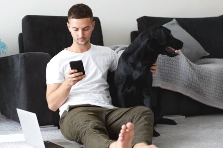 freelancer guy with laptop and dog is working at home in quarantine to coronavirus infectionの写真素材