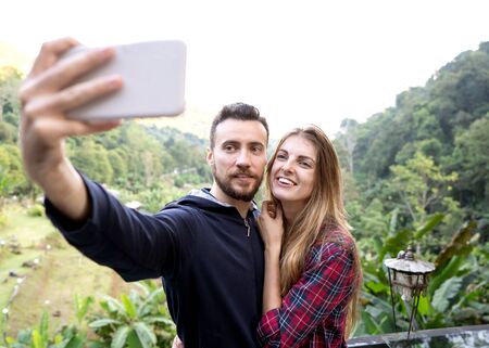 couple of tourists take selfie at sunset in the mountains of Thailandの写真素材