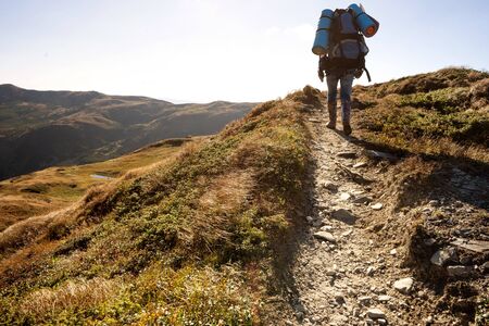  tourist goes to the mountains on a hike at sunsetの写真素材