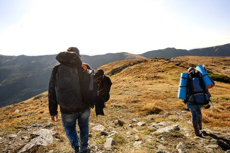 tourists go to the mountains on a hike at sunsetの写真素材