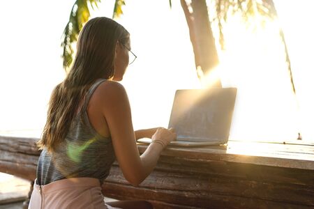 freelancer girl sitting working on her veranda by the sea in europeの写真素材