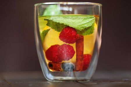 fruit tea in a transparent cup with raspberries lemon mint and cinnamonの写真素材