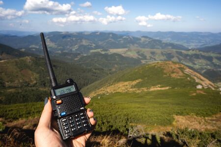 a tourist in the mountains holds a walkie-talkie to contact the groupの写真素材