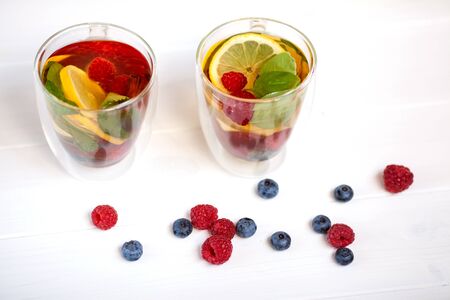 fruit tea in a transparent cups with raspberries lemon mint and cinnamonの写真素材