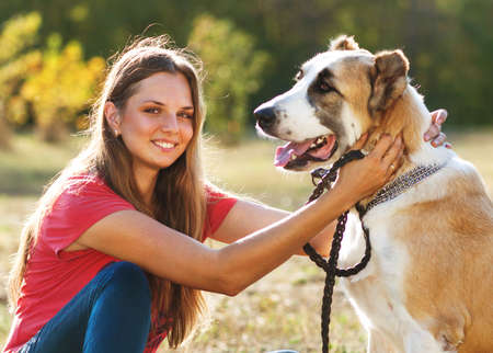 girl with her Central asian shepherd dog in autumn sunny parkの写真素材