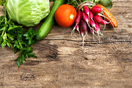 Exposition of fresh organic vegetables on woodetable. Tomatoes, cabbage, radish, cucumber, parsley,...