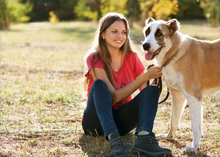 girl with her Central asian shepherd dog in autumn sunny parkの写真素材