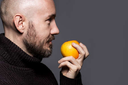 Fashion Portrait of a 40-year-old man standing over a light gray background in a black sweater. Close up. Classic style. Bald shaved head. Copy-space. Studio shotの写真素材