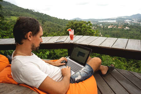 freelancer guy sits working overlooking an island in Thailandの写真素材