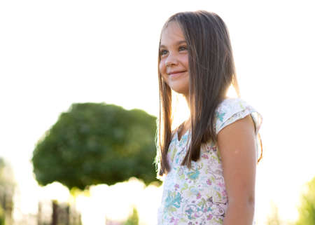 beautiful girl of 8 years old posing on a backyard near her house at sunsetの写真素材
