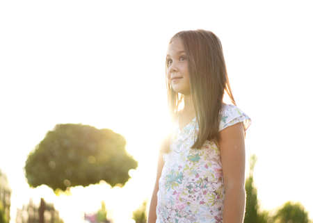 beautiful girl of 8 years old posing on a backyard near her house at sunsetの写真素材