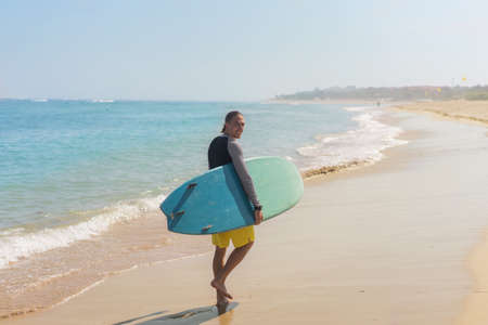 surfer guy with board walking on ocean beach