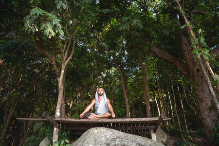 guy is meditating while sitting in the jungle in nature, concentration and calmnessの写真素材