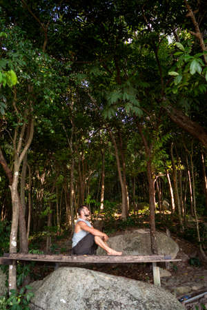 guy is meditating while sitting in the jungle in nature, concentration and calmnessの写真素材