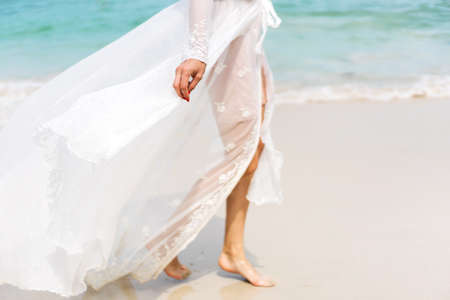 beautiful girl in a white dress walks along the beachの写真素材