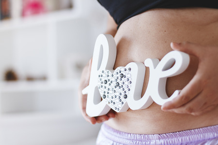 Close up of pregnant belly with word love on itの写真素材