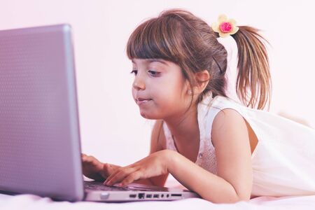 Little girl with laptop pc at homeの写真素材