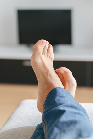 Feet of man relaxing on the sofaの写真素材