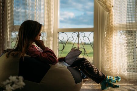 Girl works on laptop on balcony overlooking natureの写真素材