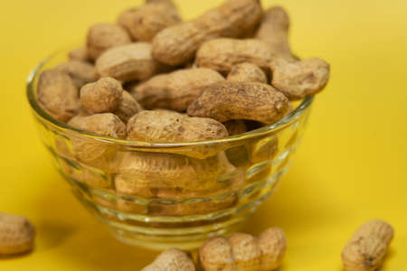 Peanuts in peel on a yellow background. High quality photoの写真素材