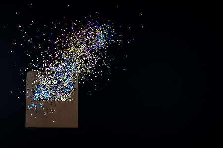 Envelope with flying out confetti on black