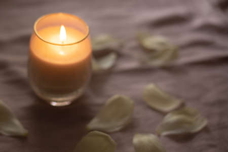 Blurred burning candle with flower petalsの写真素材