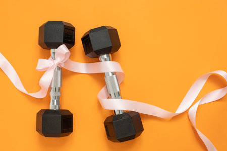 Dumbbells with bowtie on orangeの写真素材