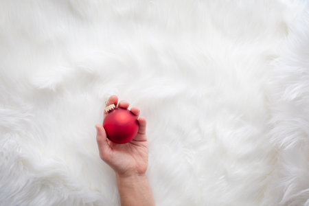 Hand holding christmas ornament on white fur backgroundの写真素材