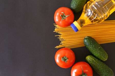 Various products. Spaghetti, pasta, tomatoes, cucumbers and vegetable sunflower oil on a gray background with place for text.の写真素材