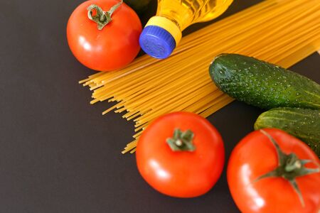 Various products. Spaghetti, pasta, tomatoes, cucumbers and vegetable sunflower oil on a gray background with place for text.の写真素材