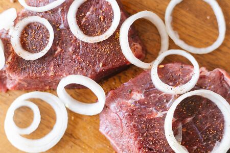 Raw beef meat with onion rings and spices on a woodenの写真素材