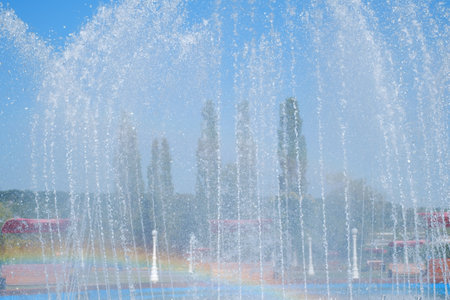 artesian fountain on blue sky with rainbowの写真素材