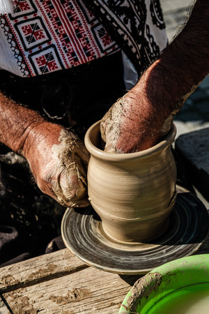 Hands of a potter shaping a clay pot on a potter wheelの写真素材