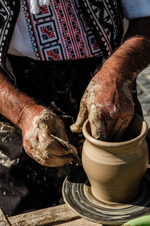 Hands of a potter shaping a clay pot on a potter wheelの写真素材