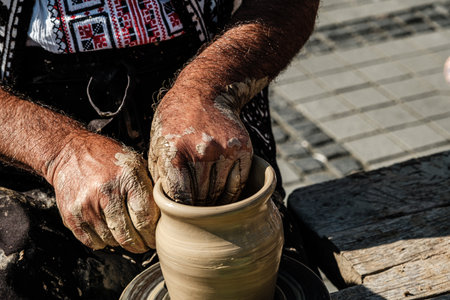 Hands of a potter shaping a clay pot on a potter wheelの写真素材
