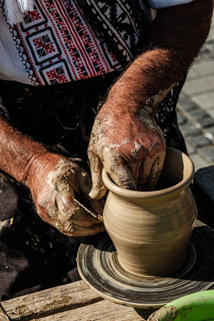 Hands of a potter shaping a clay pot on a potter wheelの写真素材
