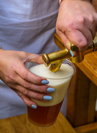 a man fills a plastic glass with beerの写真素材