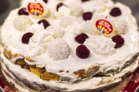 biscuit cake with whipped cream candles and cherries