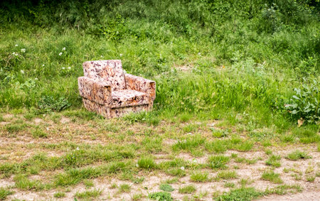 Old worn armchair sitting abandoned in tall grassの写真素材