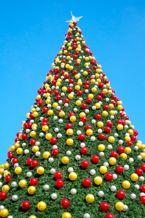christmas tree with decorates balls and large beautiful star at the top on clear blue skyの写真素材