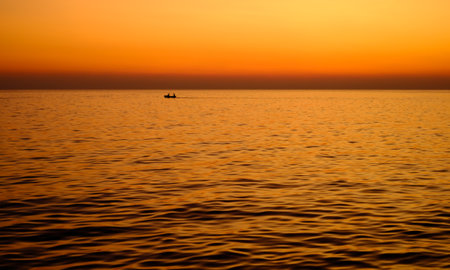 Silhuette of two man drive longtail boat to fishing in the morning on the mediterranean sea, Sliema city, Maltaの写真素材